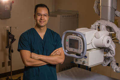  x-ray technologist Phillip Yee stands in front of an x-ray machine