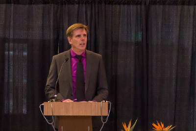 A man stands at a podium delivering a speech