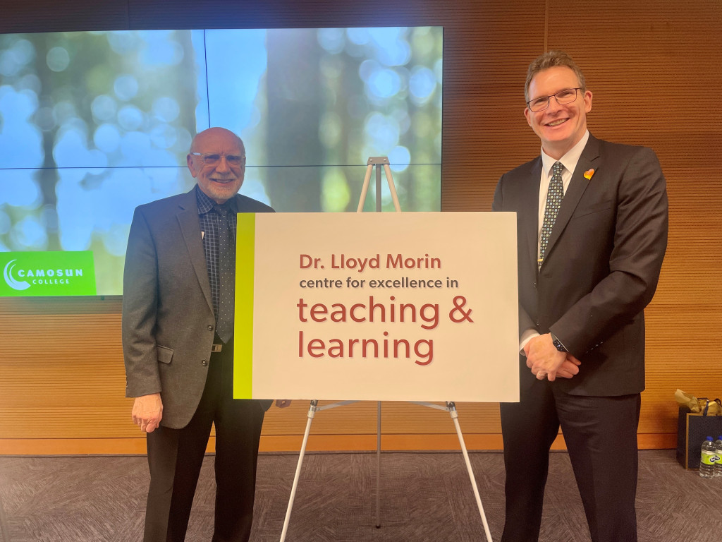 Lloyd Moring and Lane Trotter stand in front of a sign announcing the new building.