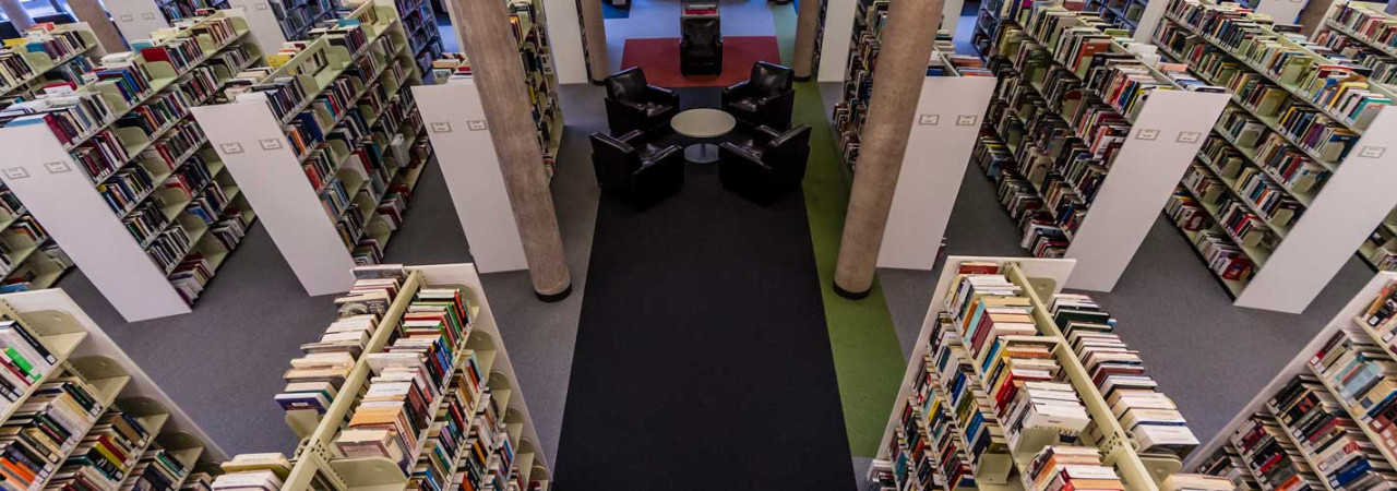 Rows of shelved books in library and 4 chairs