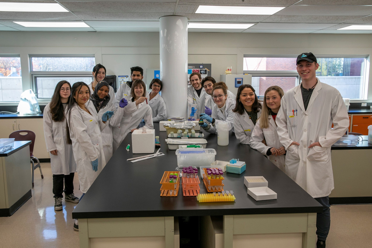 A group of biology students and instructor posing for group photo in the lab
