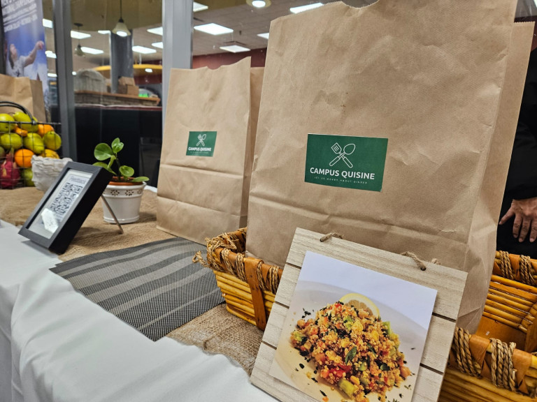 Paper bags with small green labels reading 'Campus Quisine' full of meal kits for students