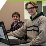 Two students on their laptops within the classroom