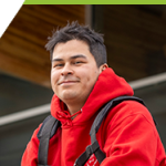 Jason sitting and smiling in front of the CTEI building in the Interurban Campus.