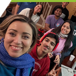 A group of smiling people posing together for a selfie.
