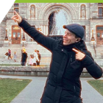 1. A man in a black jacket and hat points towards a regal looking parliament building in downtown Victoria, B.C..