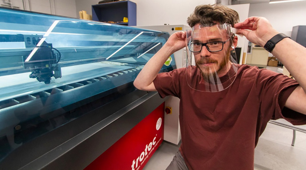 A technician tries on a newly manufactured face shield