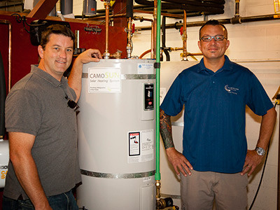 Darren Vaux poses beside an energy efficient hot water tank 