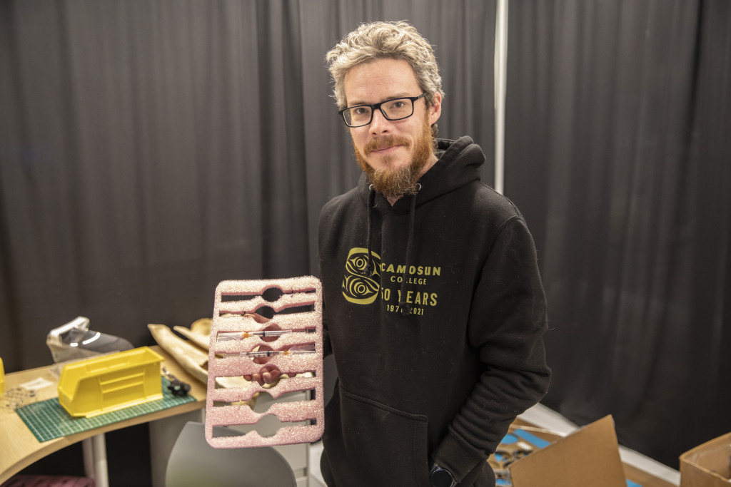 A man shows off a pink tray used to hold pre-drawn vaccine doses