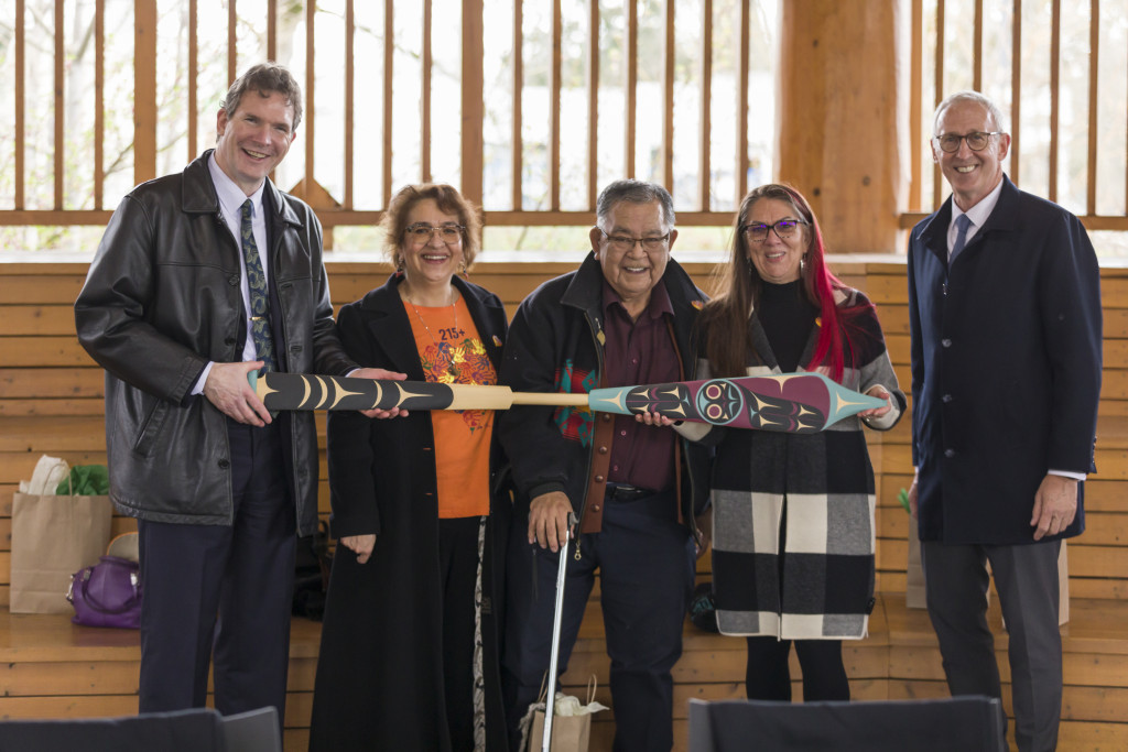 Camosun and UVic group holding a paddle.