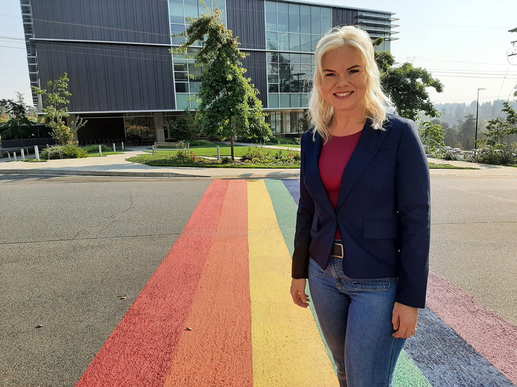 Liisa Robinson, Manager, Counselling and Student Wellness standing in front of the rainbow crosswalk
