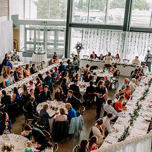 A large wedding reception in large filled with windows and light.