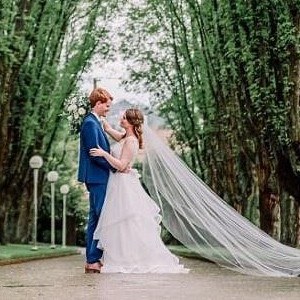 A bride and groom under a natural archway of trees.