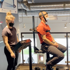 Sports co-op student looking a the screen of a machine to assess a client sitting in front of her.