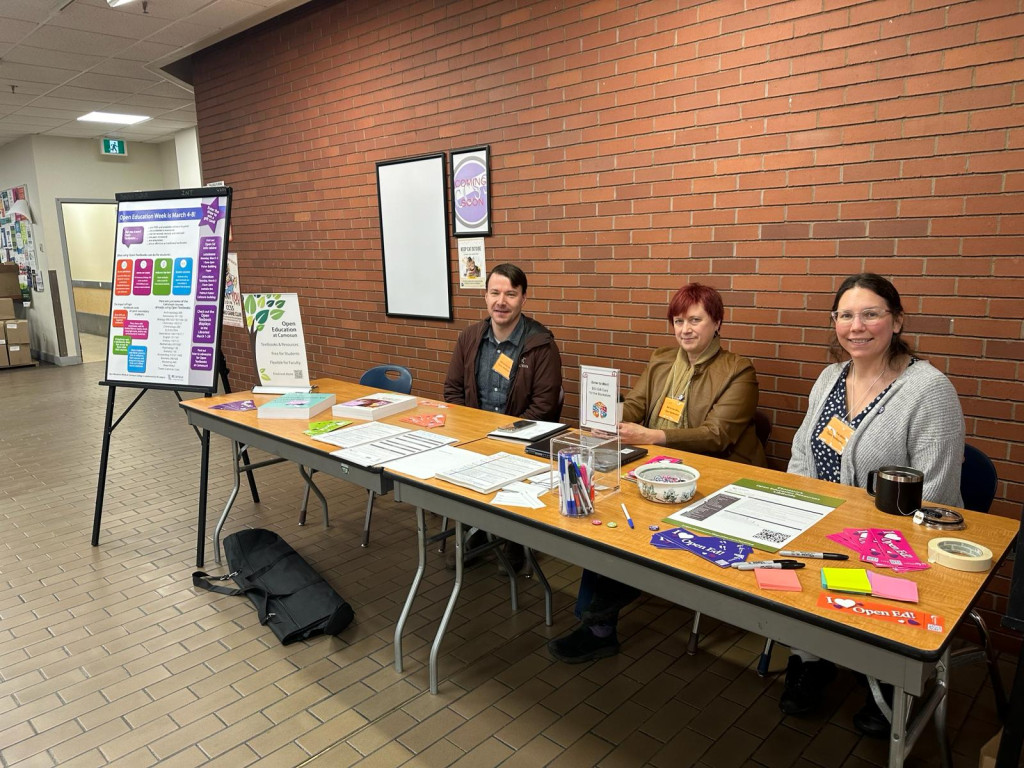 Camosun College staff sit behind a table that has information on open education resources.