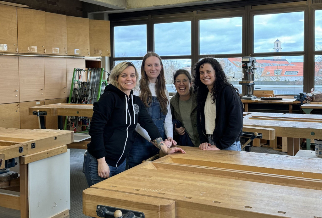 Four women stand together in a wood working shop