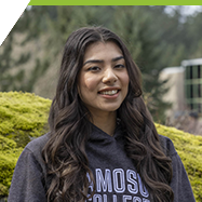 Sabrina sitting outdoors, in front of the Centre for Business and Access, wearing a Camosun College hoodie.