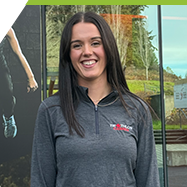 Camosun alumna Ella Calder smiles for the camera as she stand in front of of the athletics centre. 