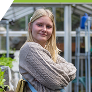 Kyla standing in the greenhouse, smiling