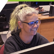 A young woman works at a computer in a large computer lab.