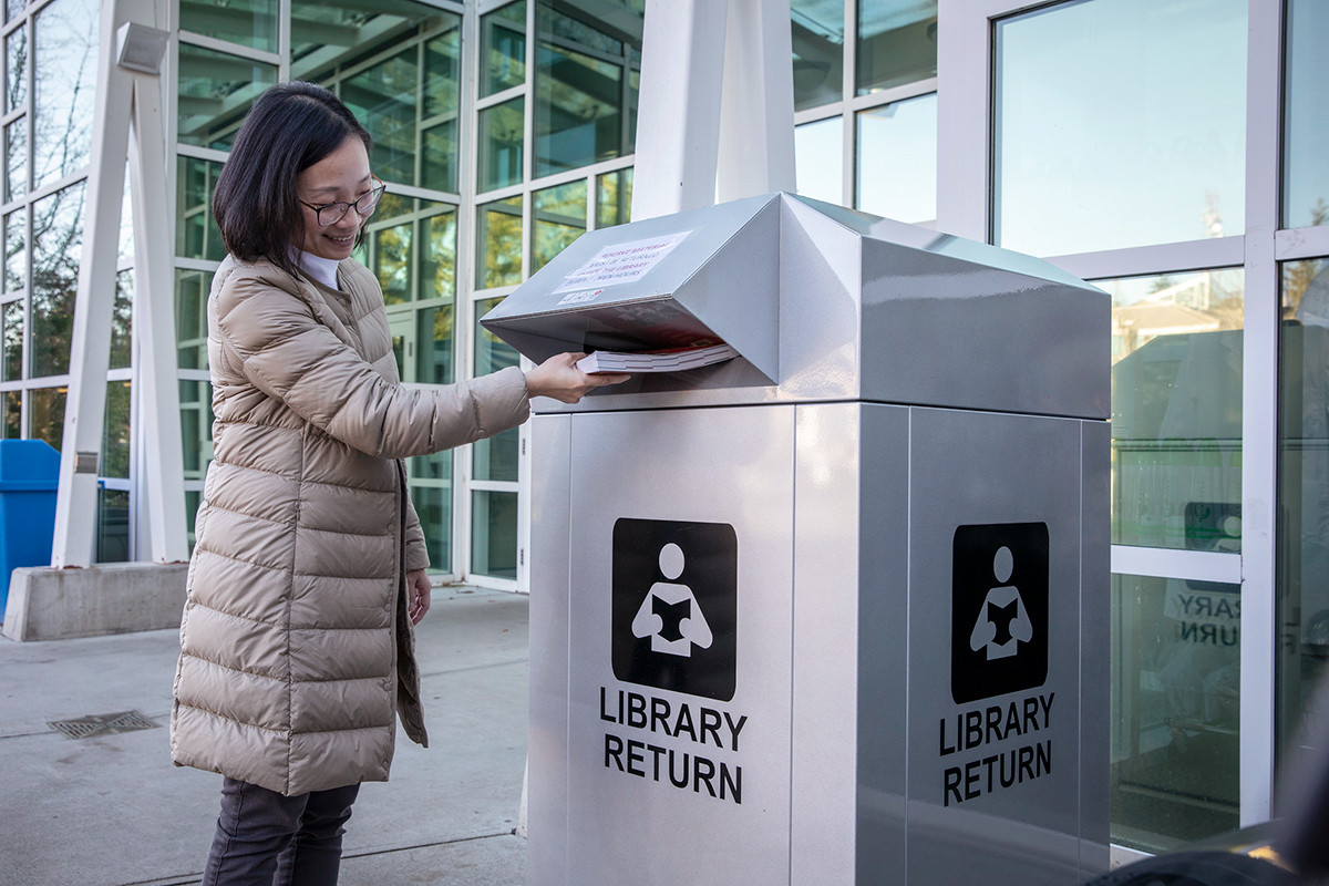 a person drops a Library book into a return bin