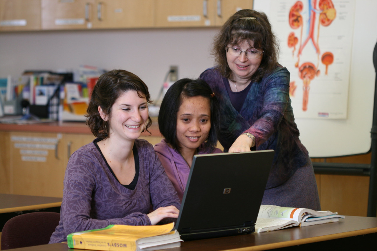 instructor and two students collaborating at a computer