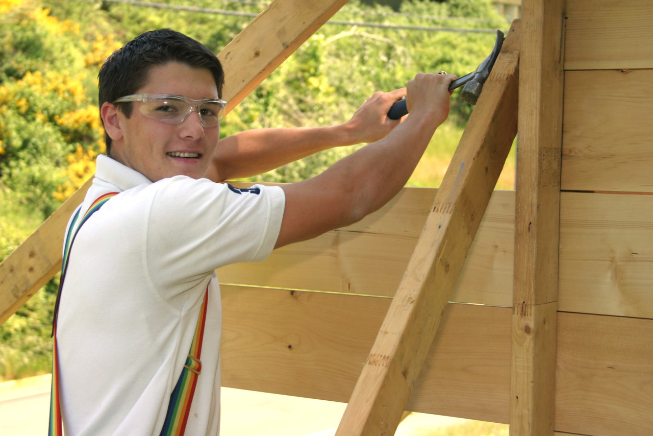 A carpentry student works on framing a house.