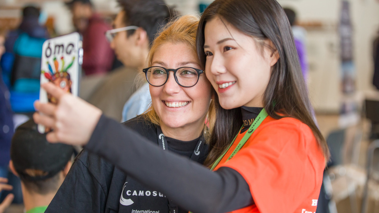 An international student takes a selfie with a College Staff member