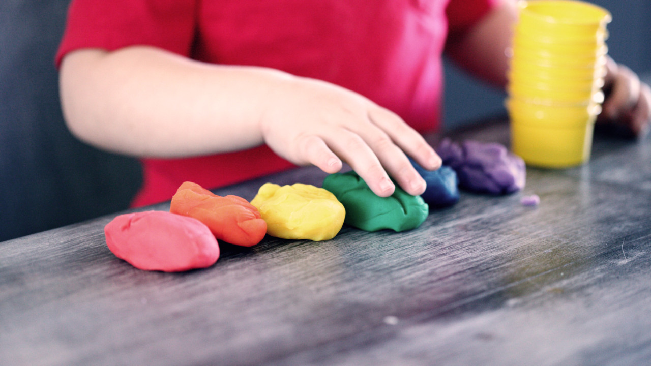 a toddler plays with a  rainbow of playdough