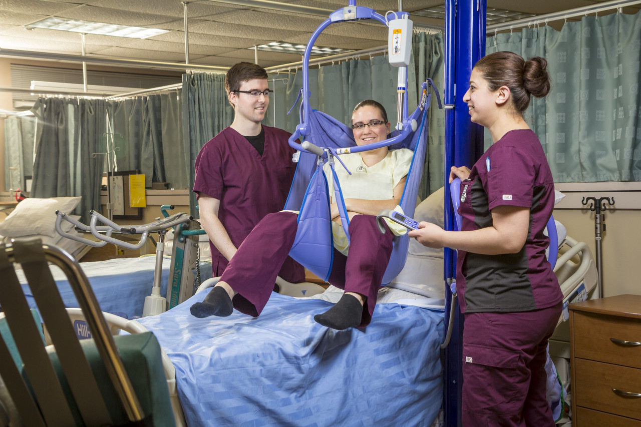 Health Care Assistant students practice using a medical lifting device
