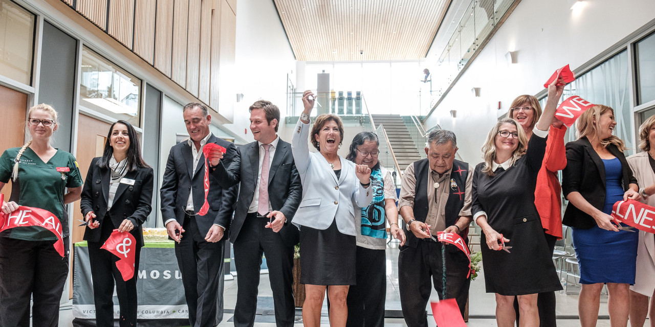 A group celebrates at as Camosun's President cuts giant red ribbon at in lobby of a brand new and very modern building. 
