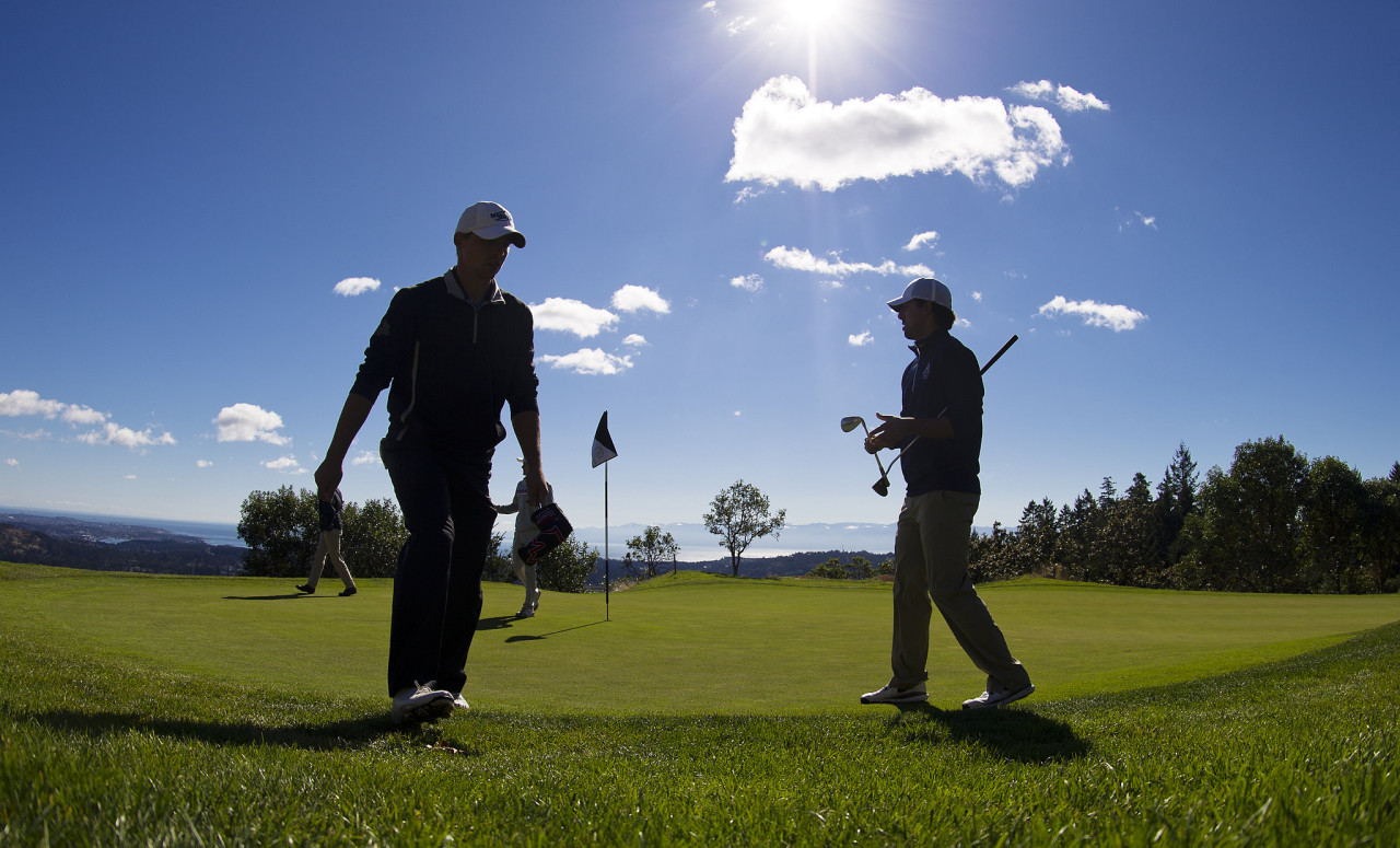 Silhouettes of people on a golf course on a bright sunny day
