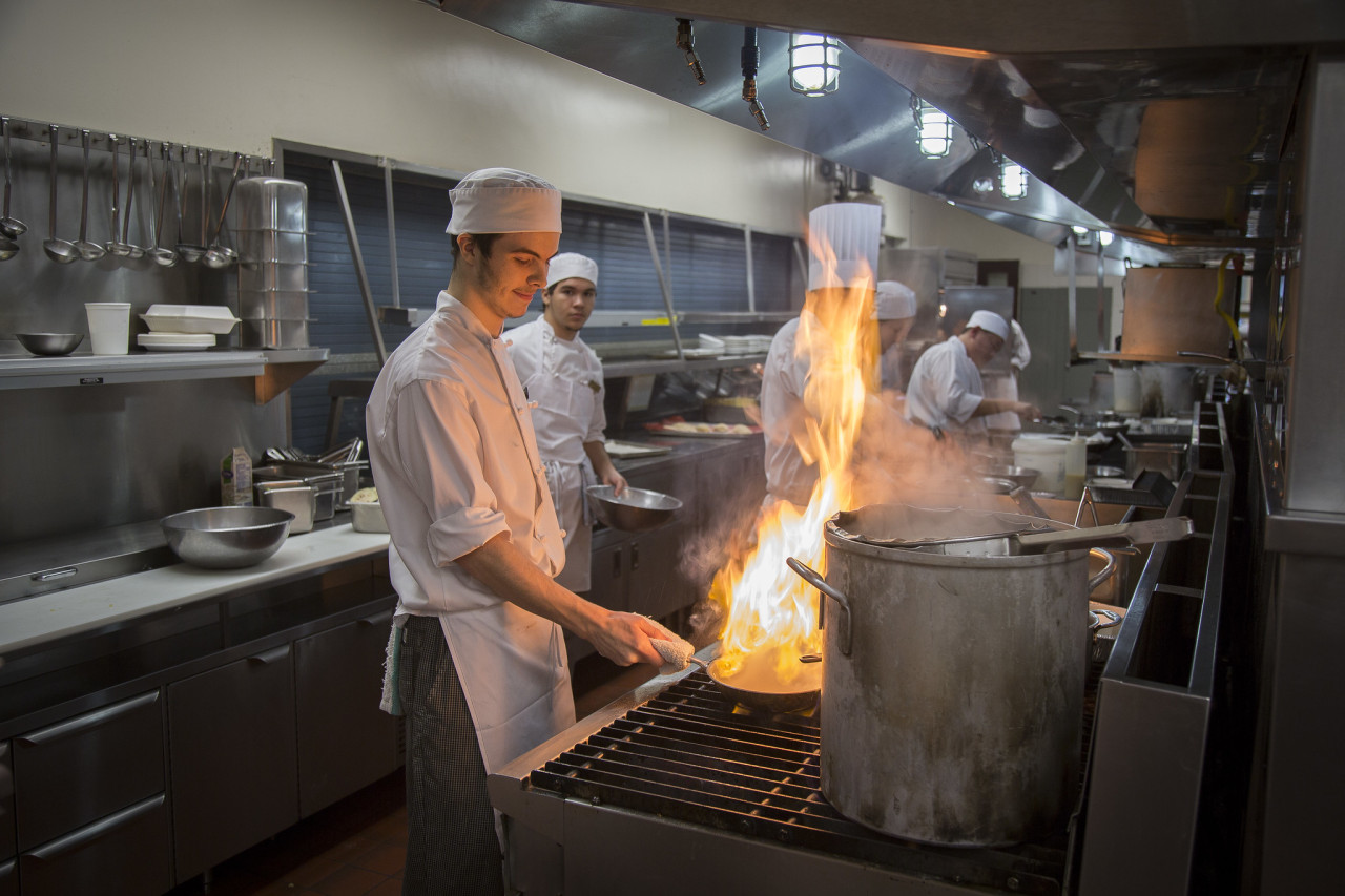 Culinary arts students in the kitchen with flames
