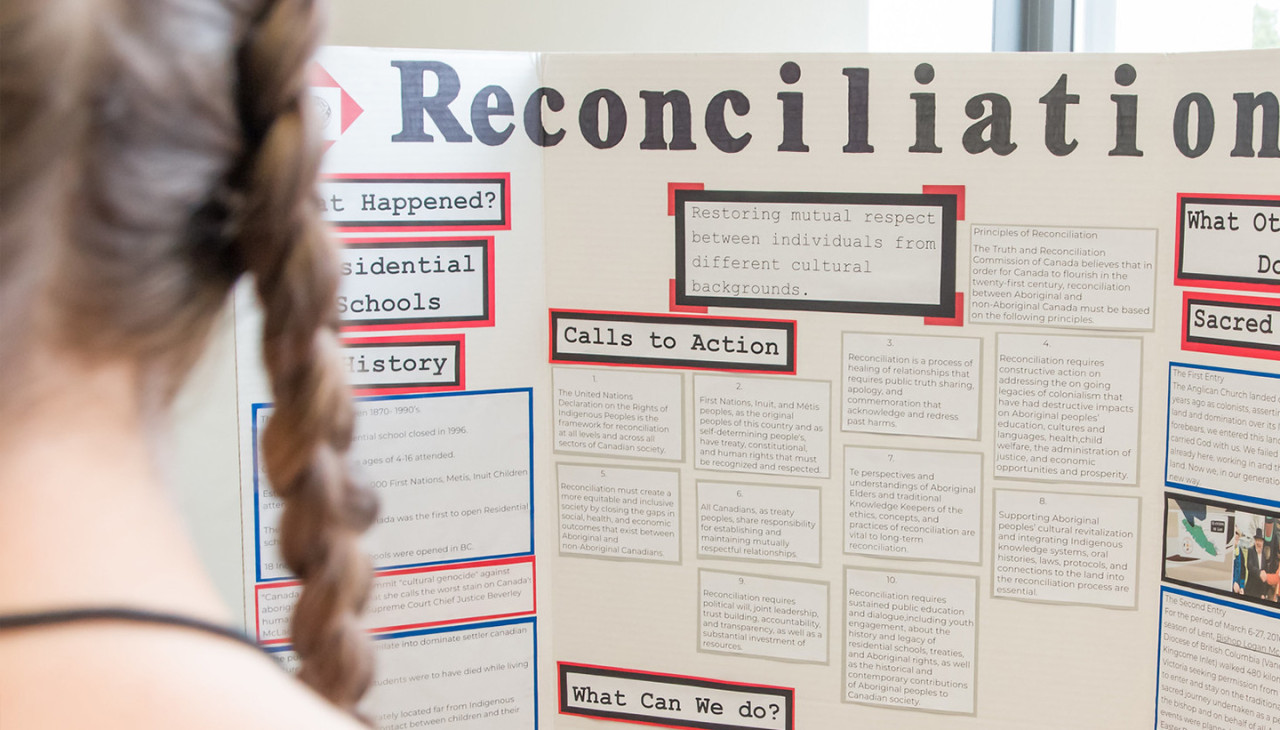 A student explains her interdisciplinary reconciliation project to a Instructor