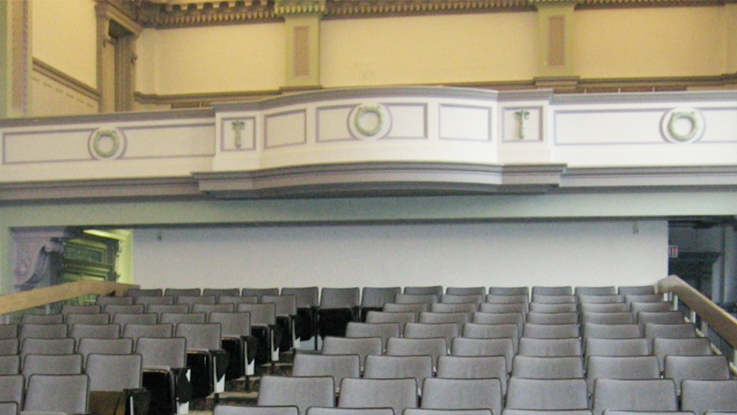 The interior of an empty auditorium with a large and ornate upper balcony. 