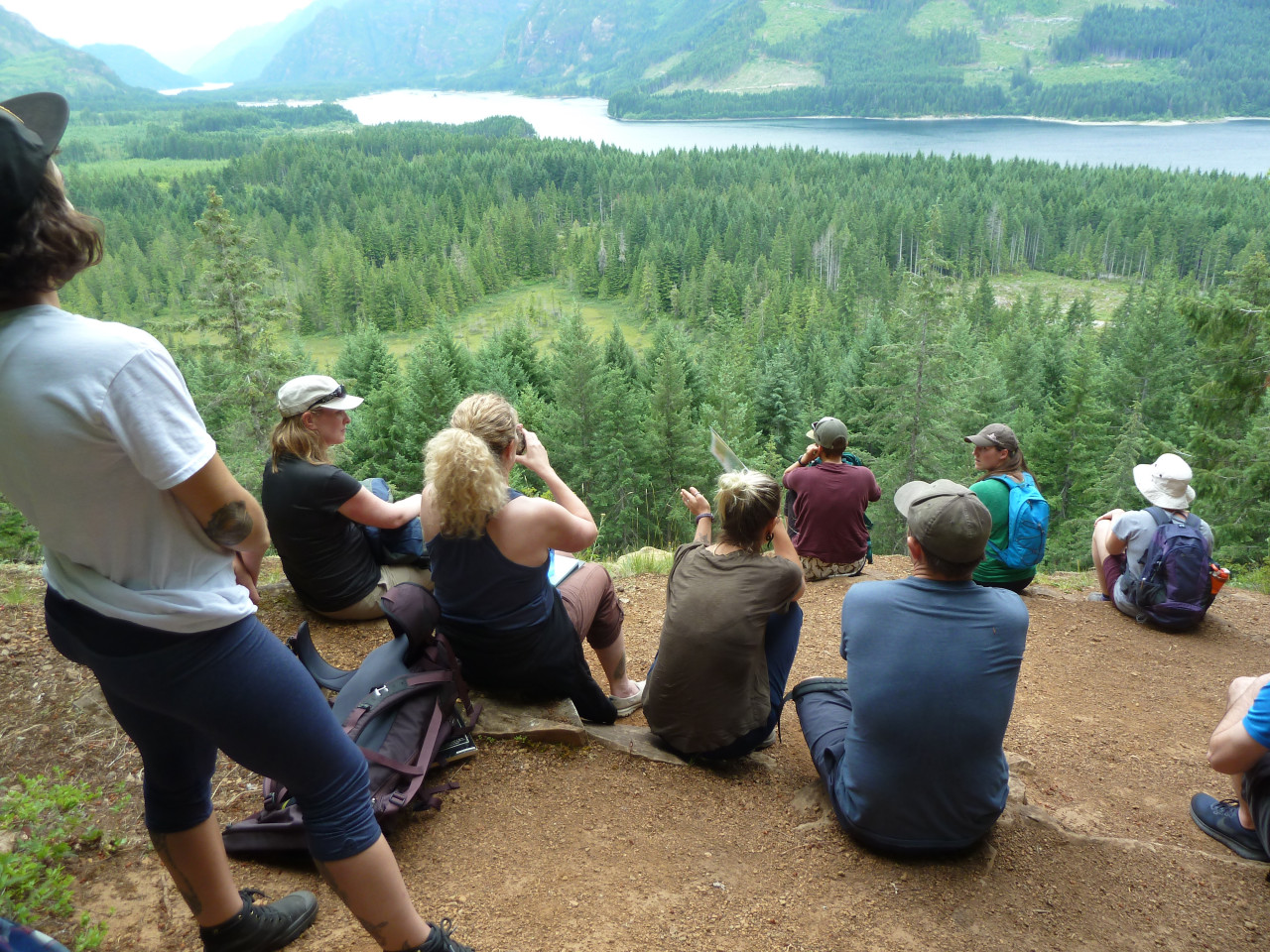 group of adventure education students on mountain hike overlooking view of lake and forest
