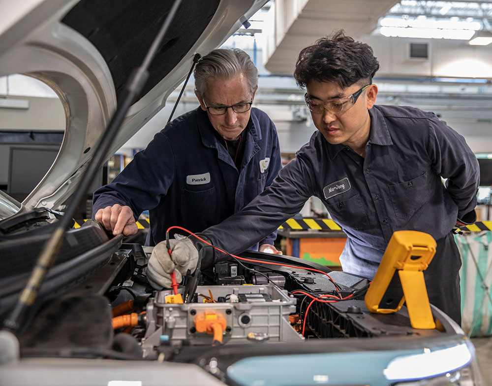 Instructor Patrick Jones with student working on an electric vehicle