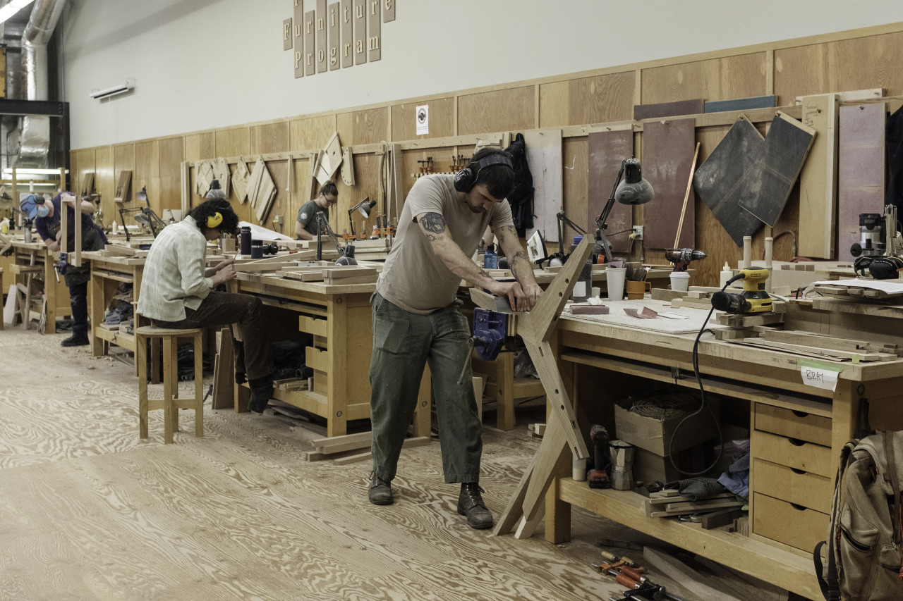 Two students from the fine furniture program are heads down and working at their separate stations.