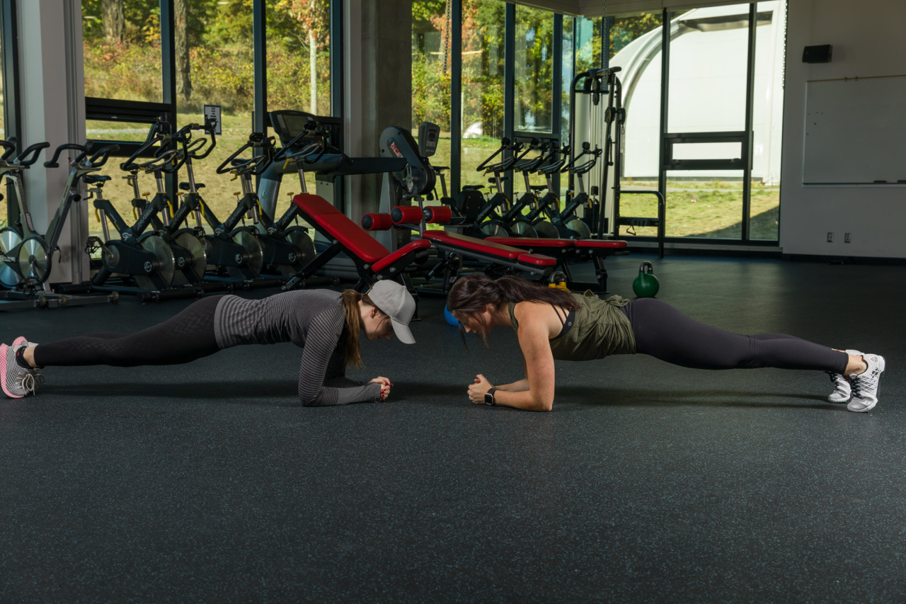 Two students holding plank position while exercising in the PISE movement studio