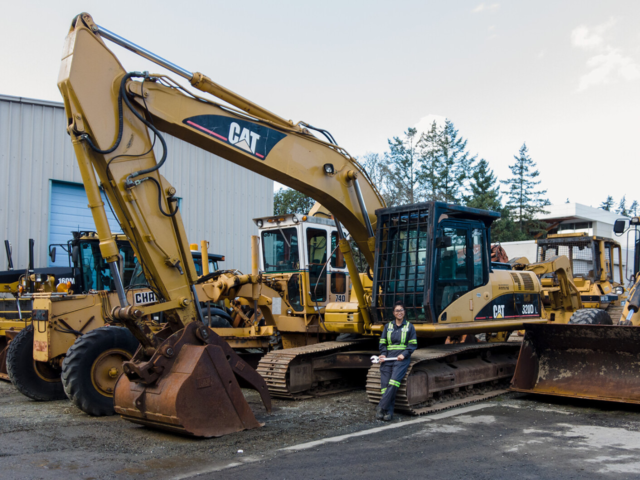 A Women in Trades student stands with heavy machinery.
