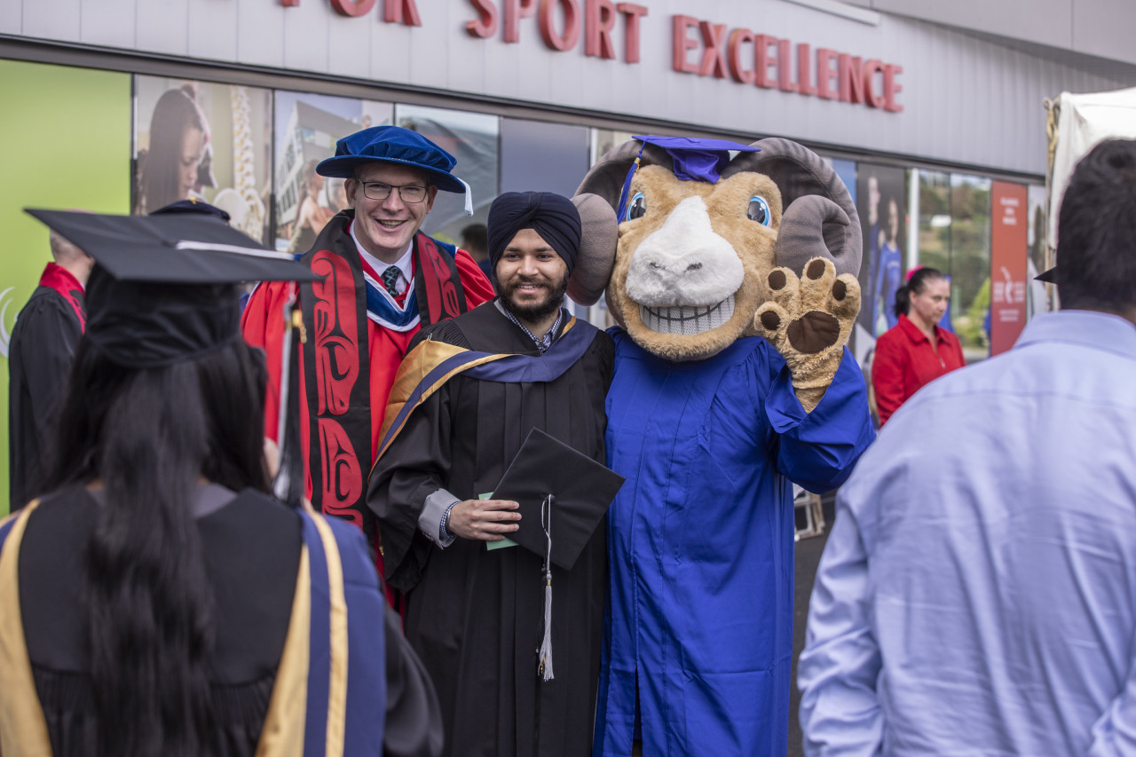 A graduating student poses for a picture with Rampage, the Camosun Chargers mascot and College President, Lane Trotter