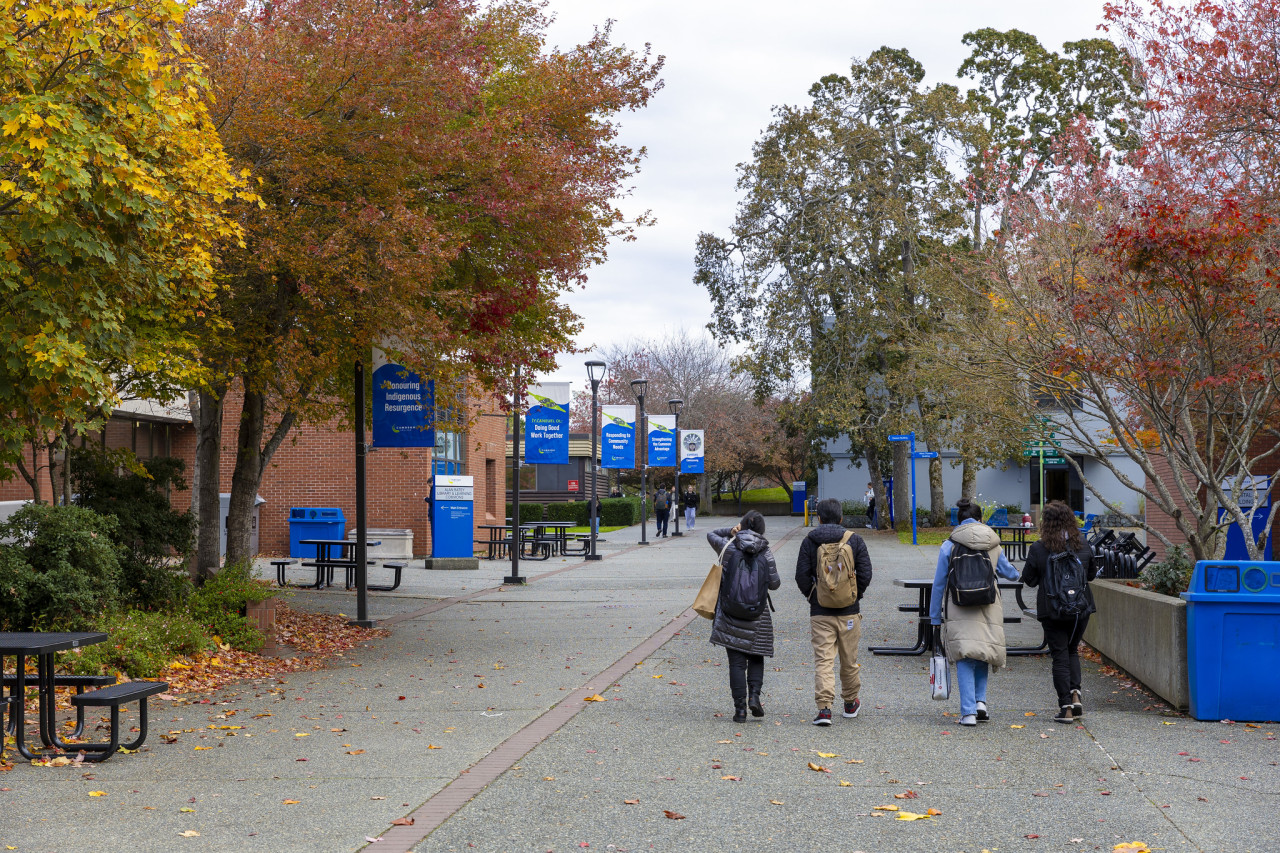 Exterior of Lansdowne campus main corridor in fall with trees changing colours and students walking 