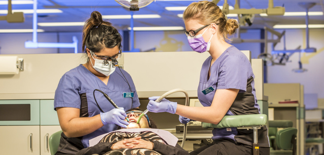 two dental students in clinic working on a patient