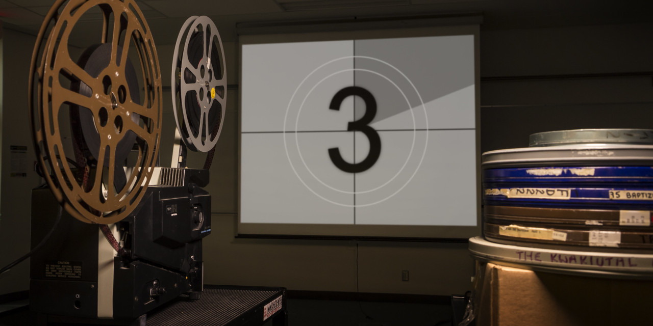 The number 3 is projected on a screen by a film projector.