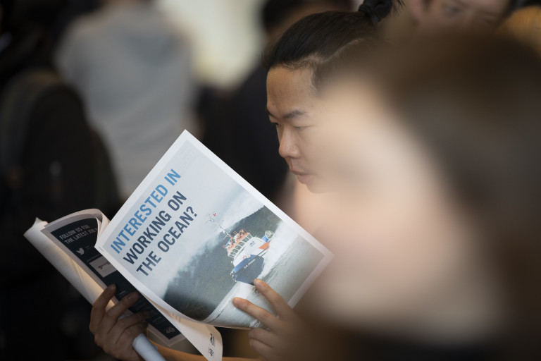 A person reads a pamphlet with the title "Interested in working on the ocean"