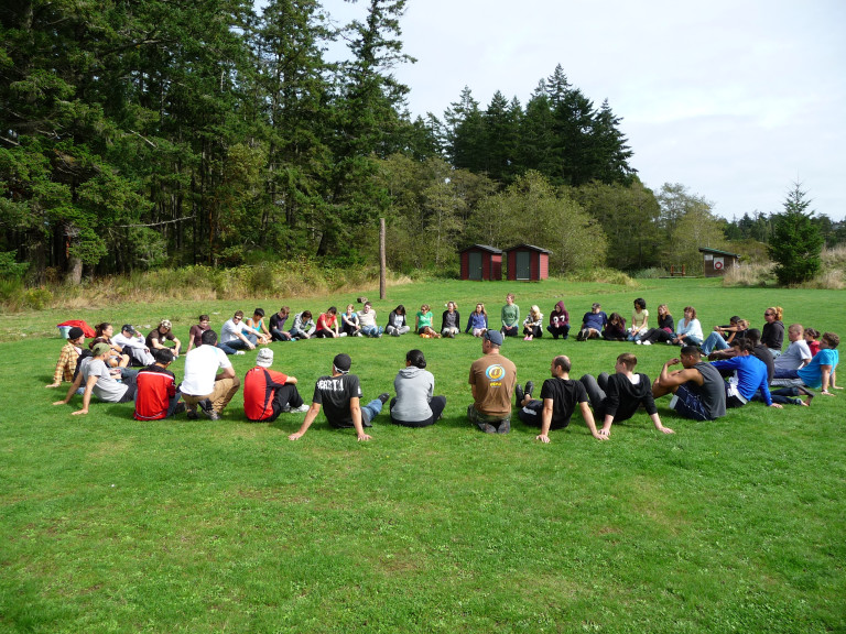 Photo of ADED students in circle in a green field