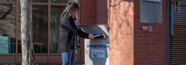 Person returning a book to outside book return structure