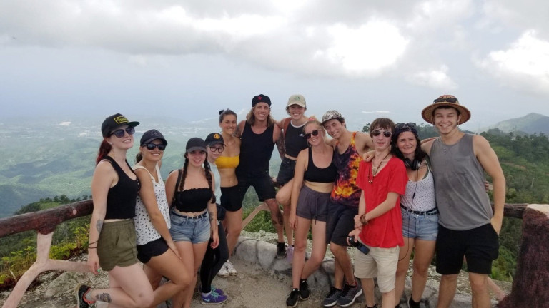 A group of students have their picture taken on a cliff overlooking the ocean