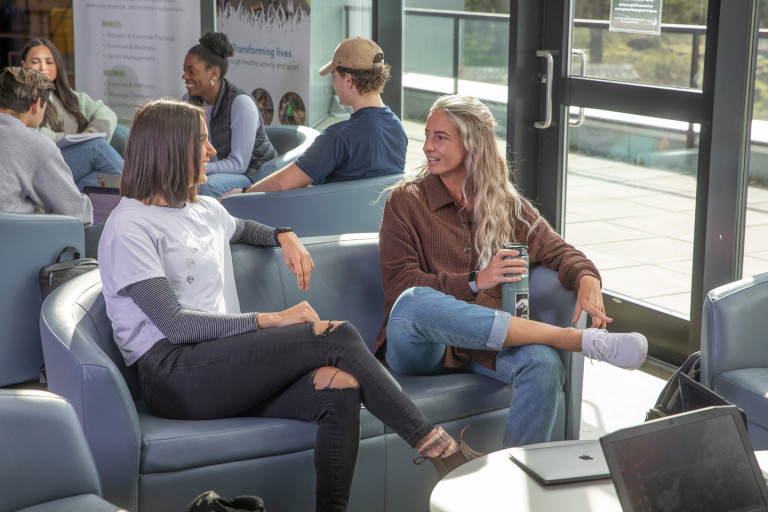 two kinesiology students chatting in study area on first floor of PISE building