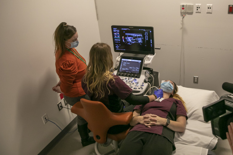 Two students demonstrate using a sonography tools in the new clinic.